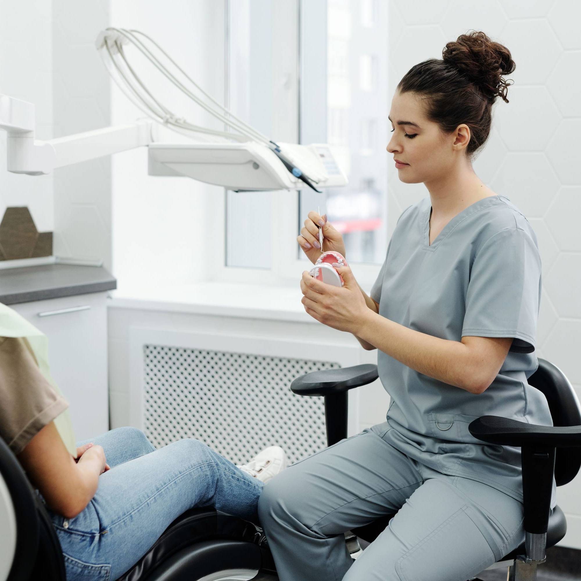 Mitarbeiterin sitzt auf Augenhöhe neben einer Patientin und spricht mit ihr vor der Behandlung