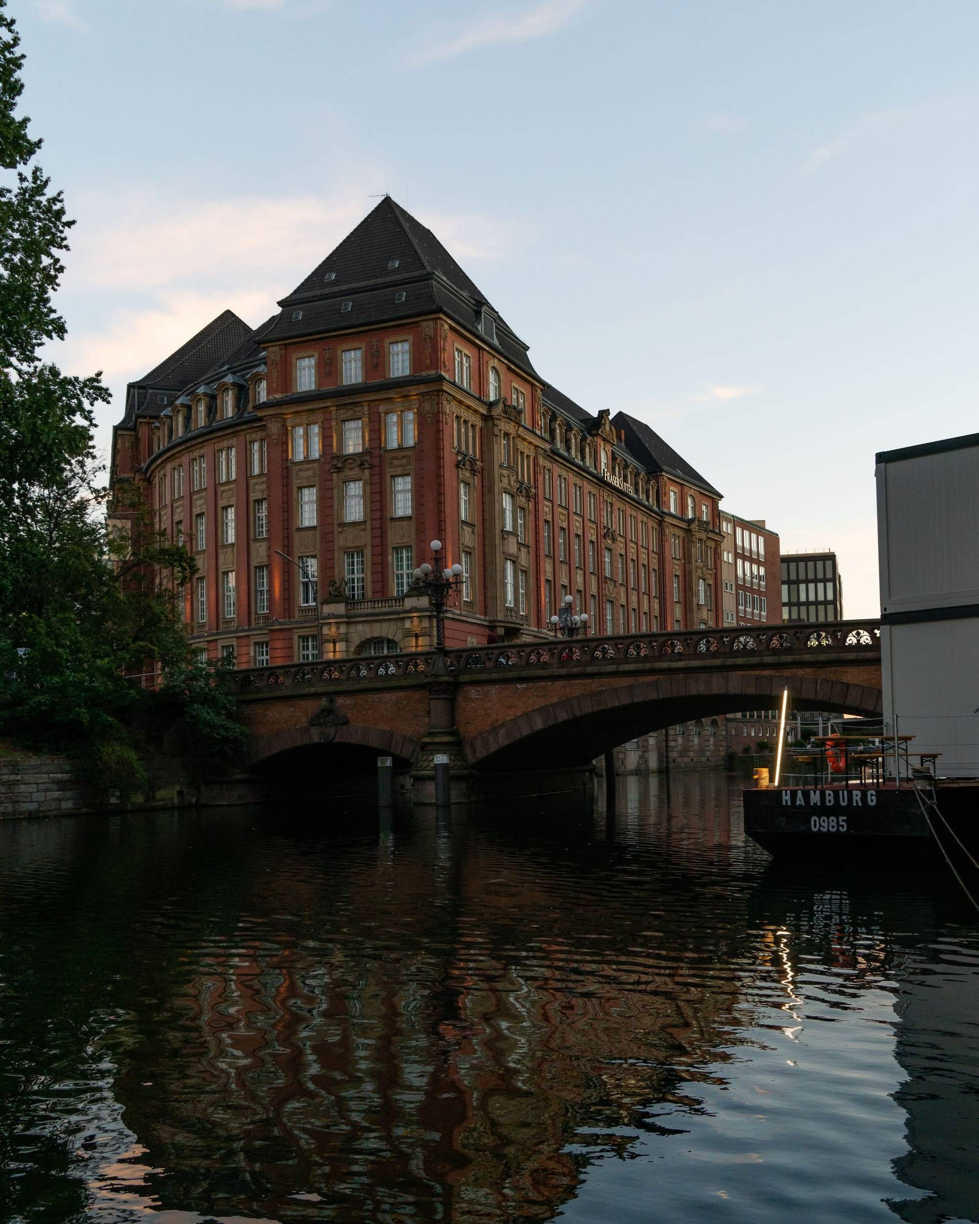 Klinkerbau an einem Hamburger Kanal mit Bogenbrücke, Spiegelung im Wasser