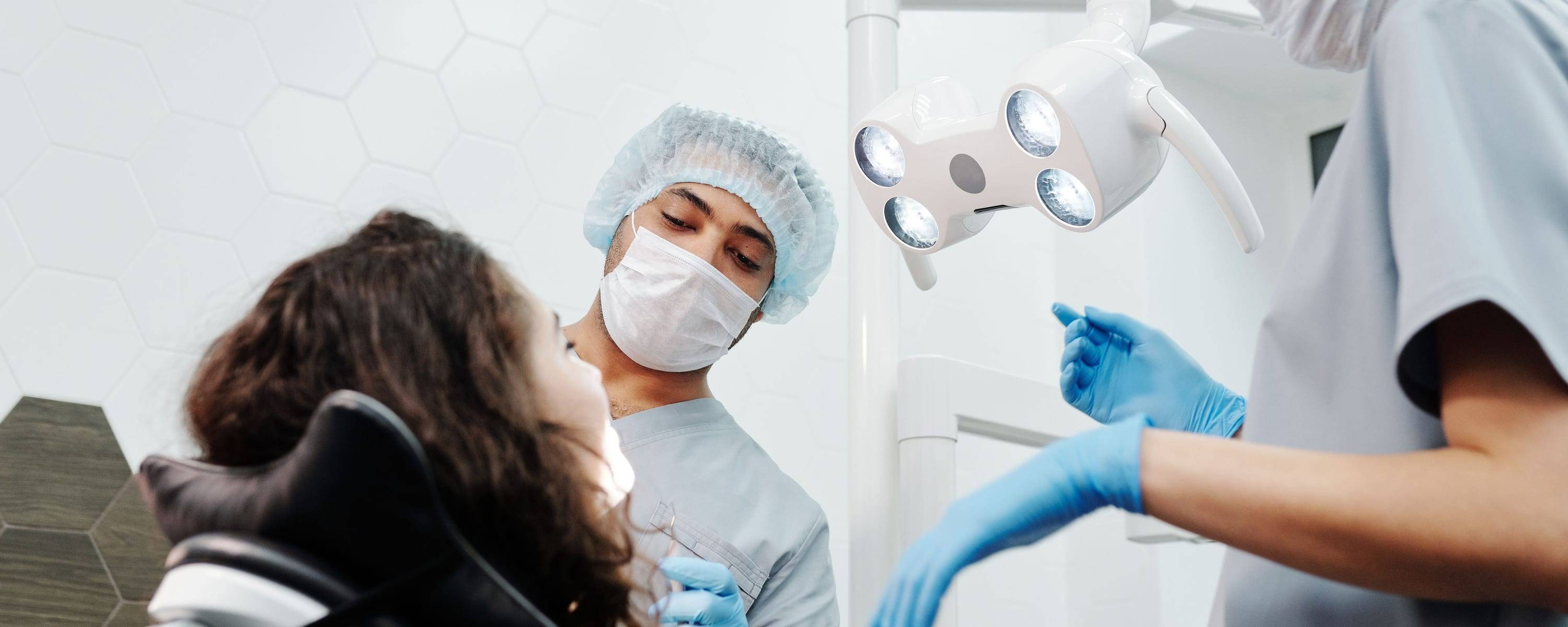 Zwei Behandlerinnen bei einer professionellen Zahnreinigung, Patientin von der Seite
