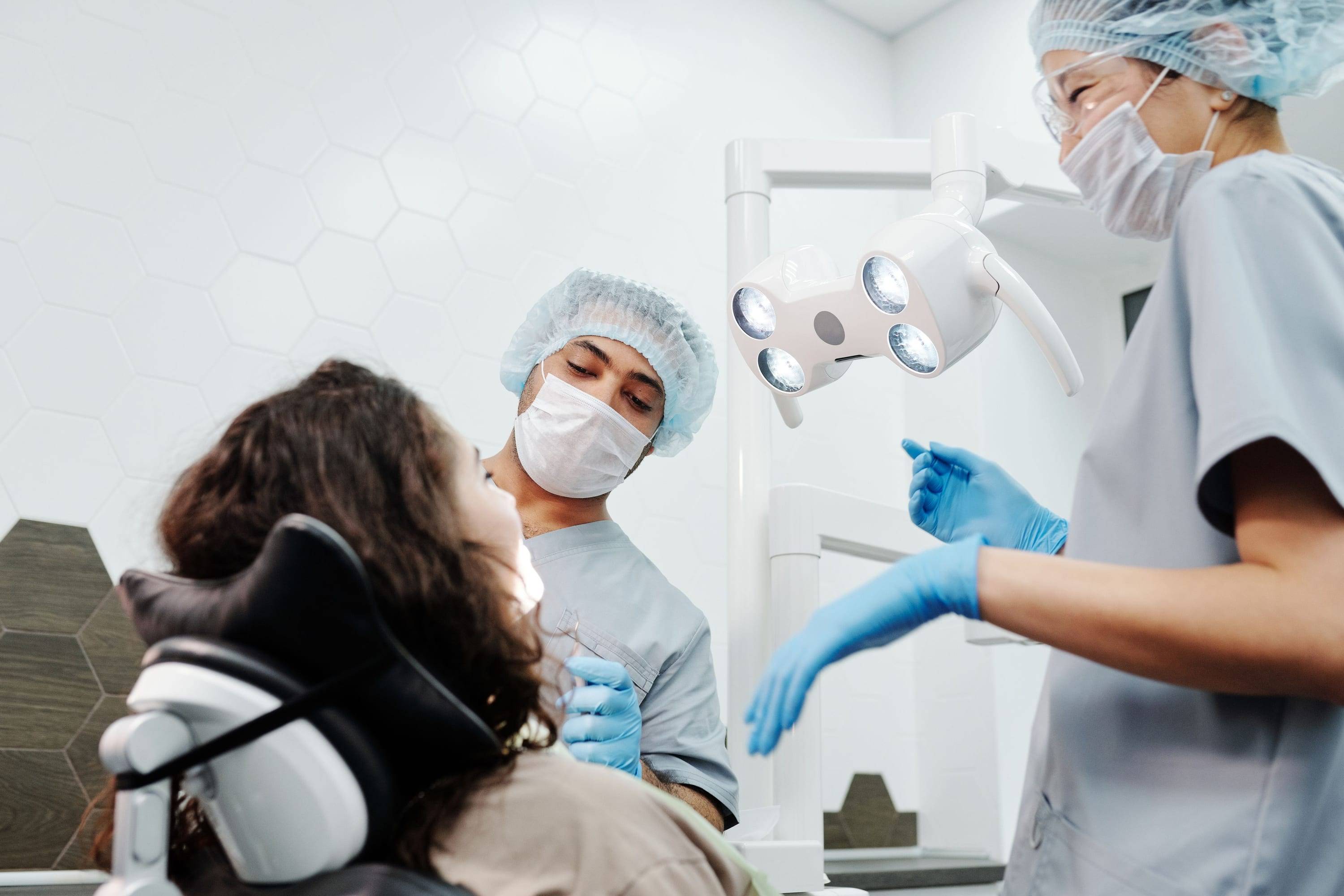 Zwei Behandlerinnen bei einer professionellen Zahnreinigung, Patientin von der Seite